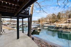 A covered outdoor area with a concrete floor, a metal table, and a tree.