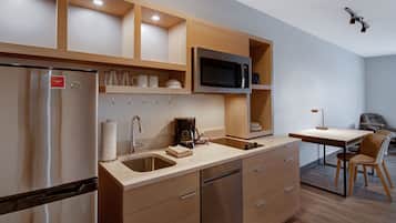 A modern kitchen with stainless steel appliances, wooden cabinetry, and a dining area with a table and chairs.