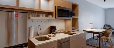 A modern kitchen with stainless steel appliances, wooden cabinetry, and a dining area with a table and chairs.