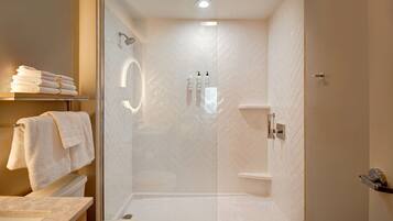 Un baño moderno con ducha de mampara de vidrio, inodoro y lavamanos.