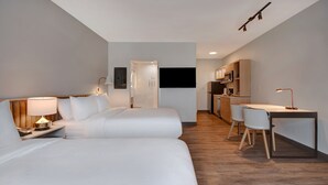 Une chambre d’hôtel moderne équipée de deux lits, d’un bureau et d’une kitchenette.