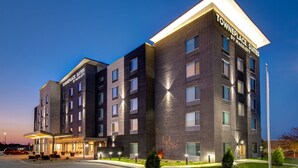 Un hôtel à plusieurs étages au design moderne, doté d’une entrée imposante avec un espace extérieur aménagé et d’une façade bien éclairée.