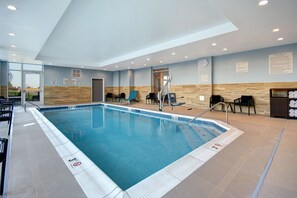 A modern indoor swimming pool with clear lane markings, a lifeguard chair, and a pool area sign. - TownePlace Suites by Marriott Cincinnati Airport South (Florence)