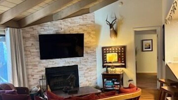 A cozy living room with a stone fireplace, a mounted television, and a deer head decoration.