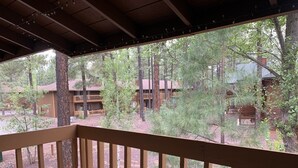 A wooden deck with a view of a forested area and buildings in the background.