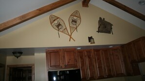 Een keuken met houten kastjes, een koelkast en decoratieve wanddecoratie.