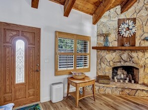 Cozy room with a stone fireplace, wooden door, and exposed beams.