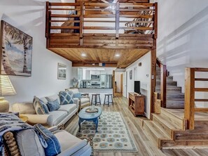 Relax in this spacious living area with a high ceiling and comfortable sofa set.