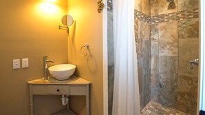 Ein Badezimmer mit Waschbecken, Spiegel und Dusche mit gefliesten Wänden.