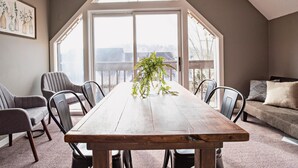Un coin repas avec une table en bois, des chaises à revêtement gris et une plante en pot.