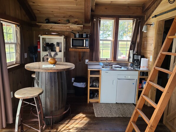 A compact kitchen with a microwave, sink, and wooden cabinets.