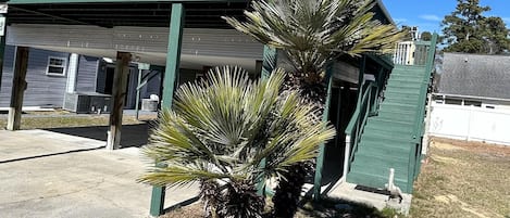 A two-story building with a green exterior and a covered parking area.