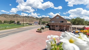 Un motel con un letrero grande, un estacionamiento y montañas al fondo.