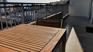 A balcony with a wooden table and chairs, a view of the sea, and a parking area in the background. - Charming T2 48m² Balcony Sea View 4 sleeps 2min from the Beach (Vallauris)