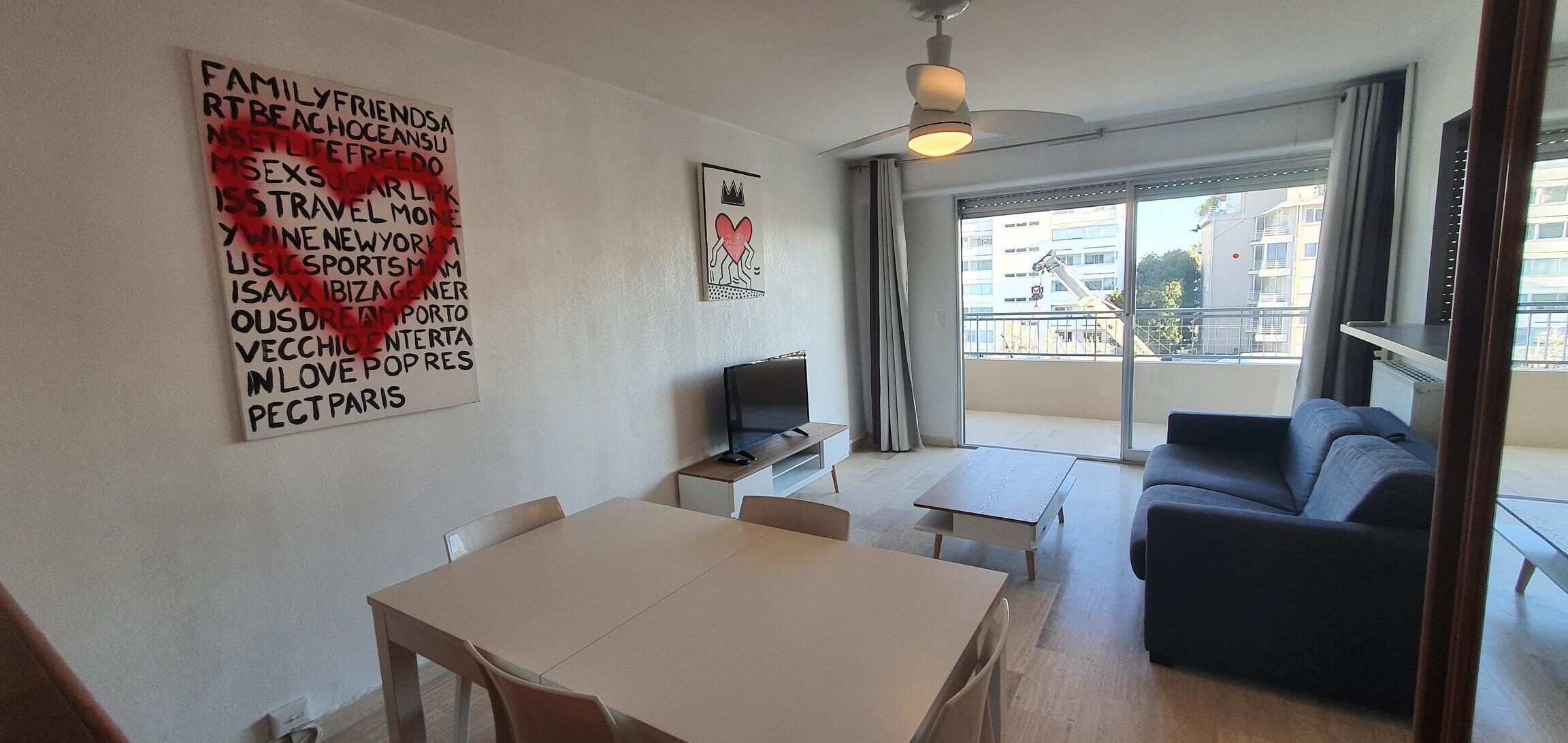 Una sala de estar moderna con comedor, un ventanal grande y un ventilador de techo.