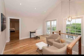 Relax in a spacious living area with a high ceiling and large windows offering a view of the outdoors.