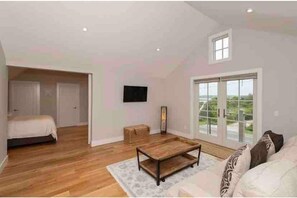 Relax in this spacious living area with a high ceiling and large window offering a view of the outdoors.