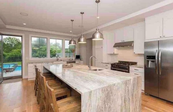 Enjoy cooking in this well-equipped kitchen with a large island, stainless steel appliances, and a view of the outdoors.