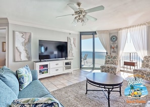 Relax in this stylish living room with a large flat-screen TV, comfortable sofa, and sliding glass door to a balcony with ocean views.