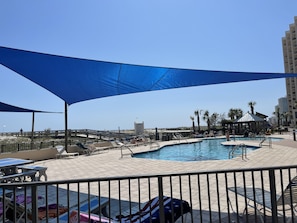 Relax by the pool surrounded by lounge chairs and umbrellas, with a clear view of the surrounding cityscape.