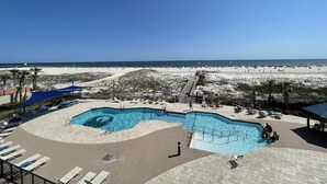 Un espace piscine avec vue sur la plage, des chaises longues et un ciel dégagé.