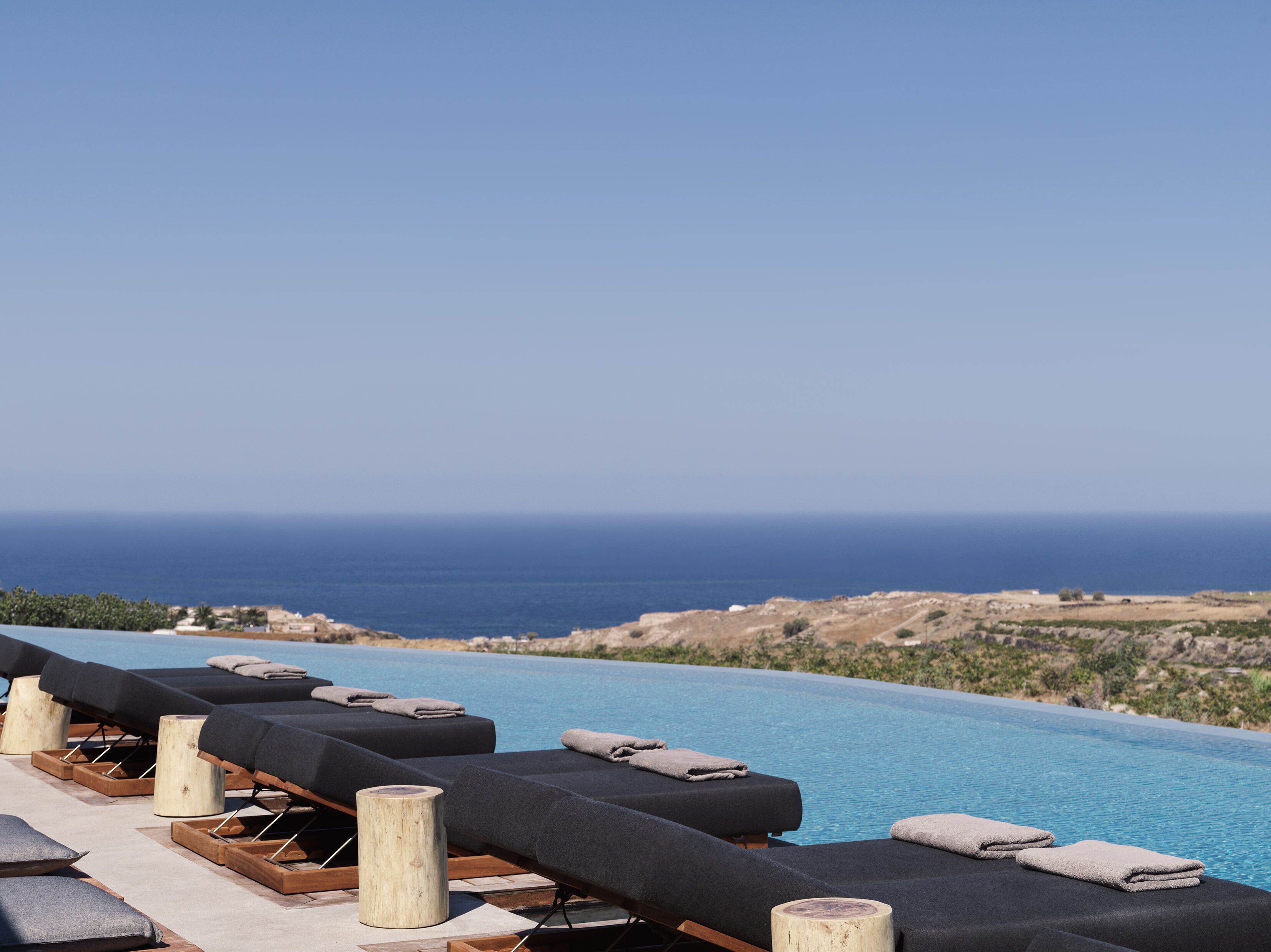 A poolside area with lounge chairs and a view of the ocean.