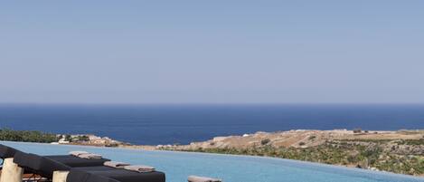 A poolside area with lounge chairs and a view of the ocean.