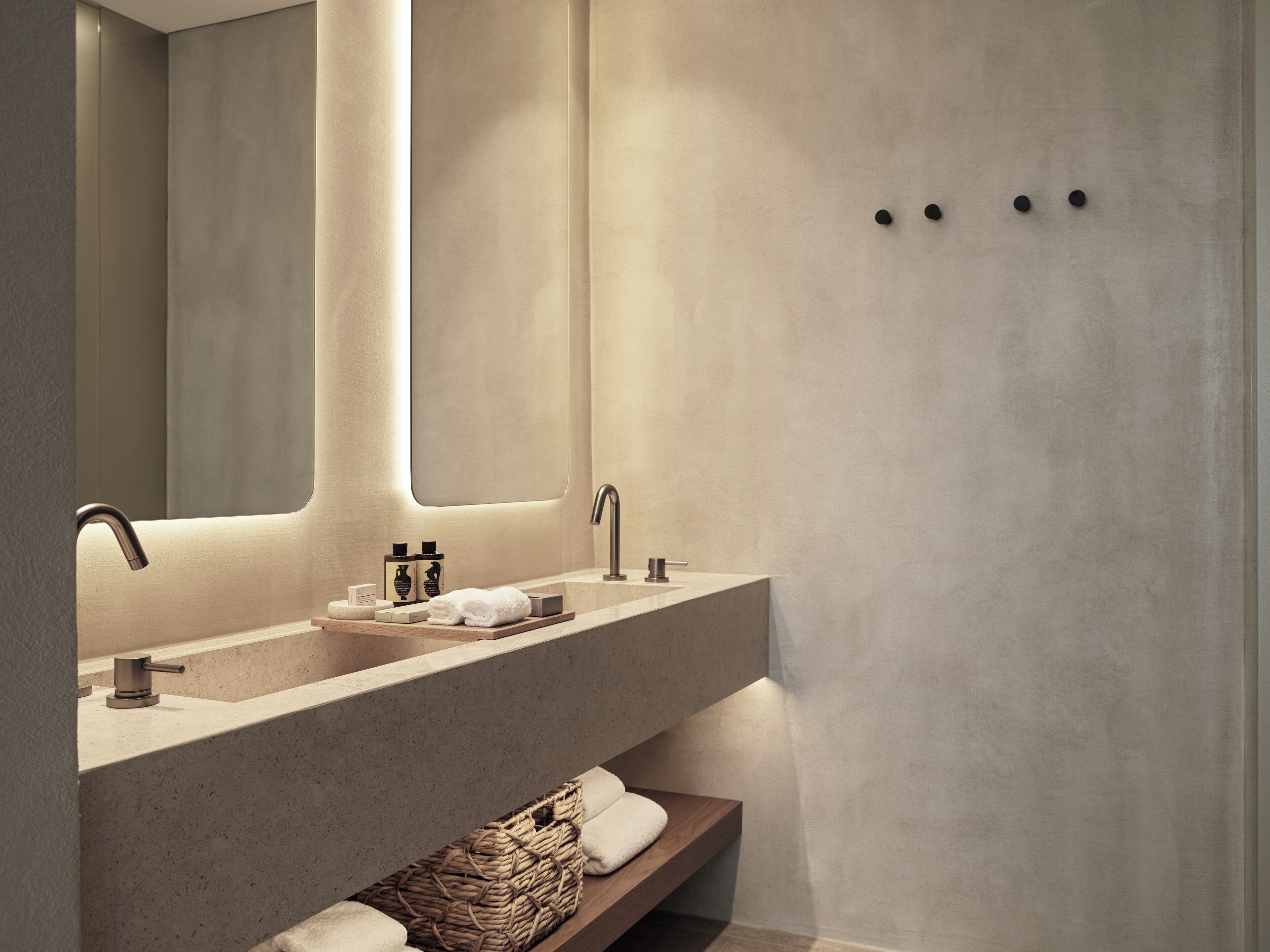 A modern bathroom with a large mirror, two sinks, and a wooden shelf with towels.