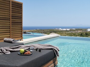 A poolside area with a towel, a plate of fruit, and a glass of water.