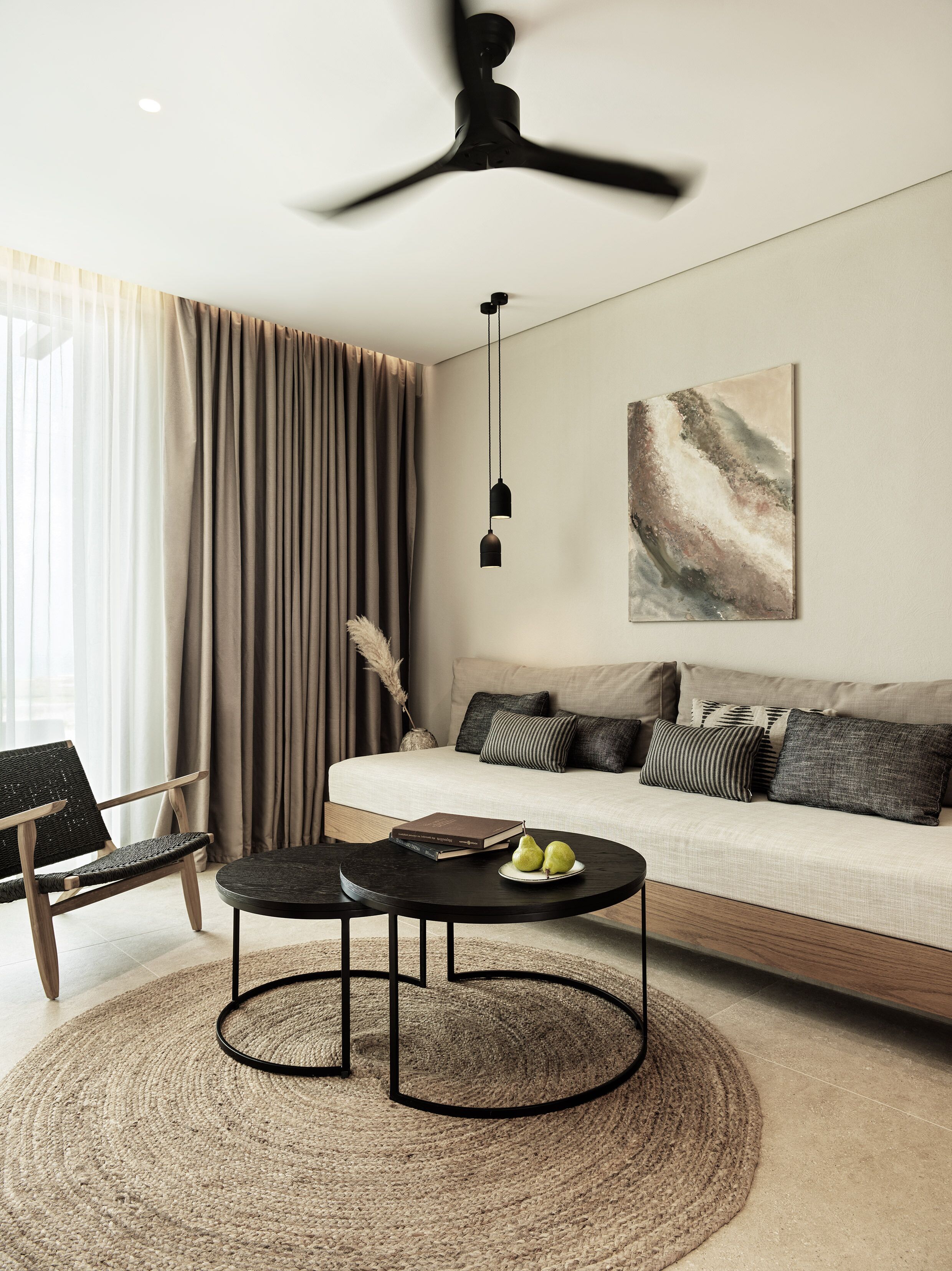 A modern living room with a sofa, a round coffee table, a chair, and a ceiling fan.