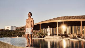 A man standing by a pool with a building in the background.