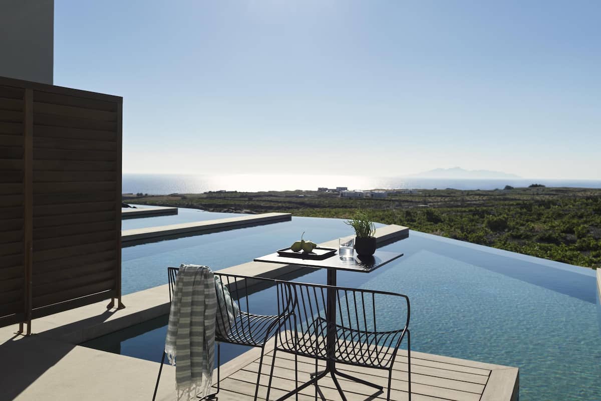 Ein Infinity-Pool auf dem Dach mit Blick auf das Meer und die entfernten Berge.