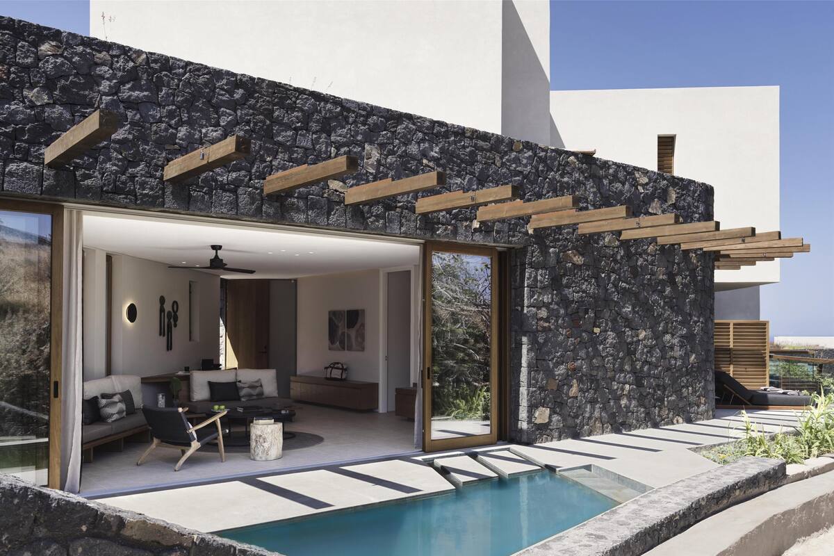 Ein modernes Haus mit Natursteinfassade, einem Pool und einem Wohnbereich mit Sofa und Couchtisch.