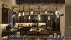 Una cocina moderna con armarios de madera oscura, una isla central y lámparas colgantes tipo Edison.