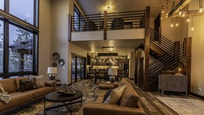 Un salón amplio con techos altos, una escalera y una zona de cocina.