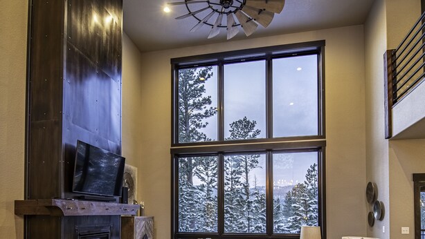 Un amplio salón con un ventanal grande, chimenea, sofá y ventilador de techo.