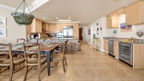 A spacious kitchen with wooden cabinets, a stainless steel refrigerator, and a dining area with a large table and chairs.