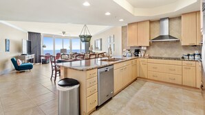 A spacious kitchen with a central island, wooden cabinets, and a large window offering a view.