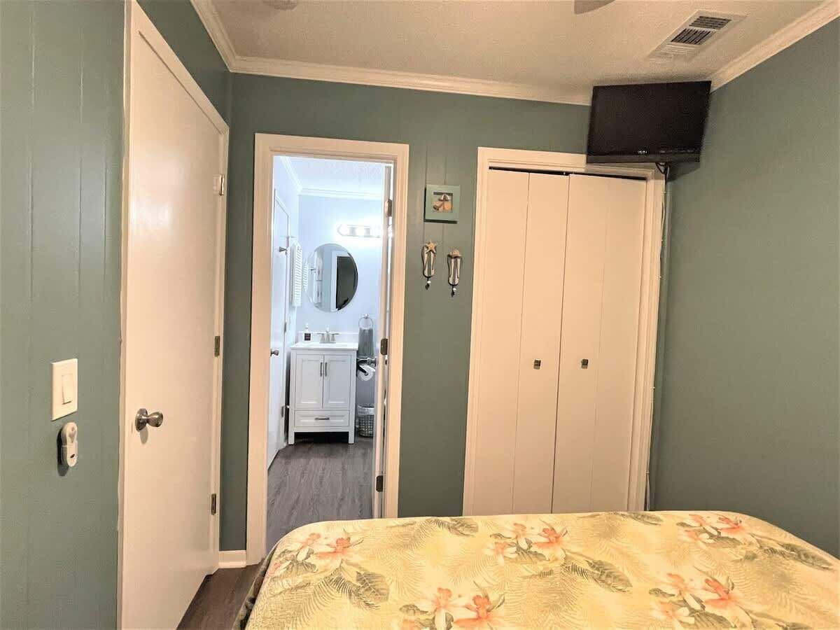 Une chambre à coucher avec un lit, une armoire et une salle de bain visible à travers une porte ouverte.