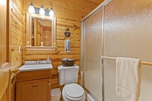 A compact wooden bathroom with a sink, toilet, and a shower area. - Beary Secluded- No Pet Fee, Hot Tub, Firepit, WiFi (Slade)