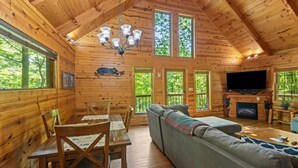 A log cabin interior with a dining table, chairs, a sofa, a fireplace, and a television. - Beary Secluded- No Pet Fee, Hot Tub, Firepit, WiFi (Slade)
