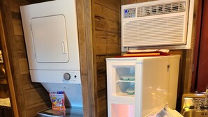 A compact kitchen with a refrigerator, a washing machine, and a built-in air conditioner. - Cute Family Cabin at Lakeview by Sue  (Appleton City)