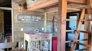 A rustic wooden interior with a sign reading "FISH STORIES TOLD HERE MOSTLY TRUE". - Cute Family Cabin at Lakeview by Sue  (Appleton City)