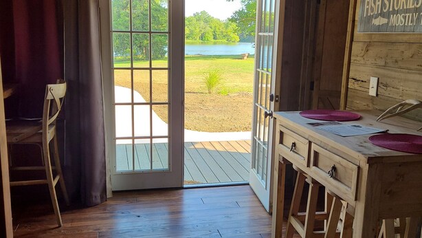 A wooden interior with a sliding glass door leading to an outdoor deck. - Cute Family Cabin at Lakeview by Sue  (Appleton City)
