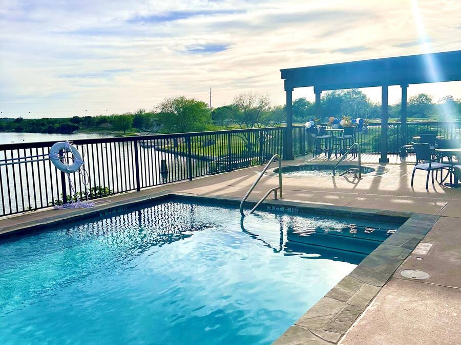A swimming pool with a lifebuoy, a covered patio area, and a view of the surrounding landscape.
