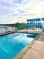 Una piscina al aire libre, sombrillas, sillones reclinables de piscina