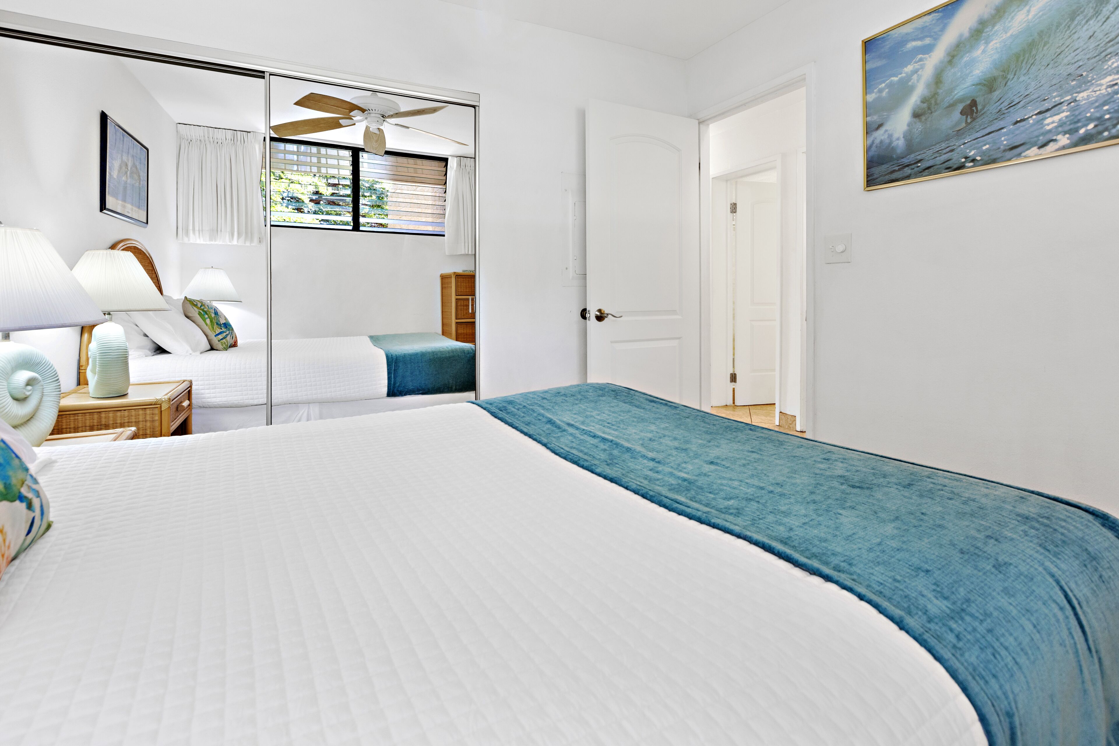 Une chambre à coucher avec un grand lit, une table de chevet avec une lampe, une armoire et un ventilateur de plafond.