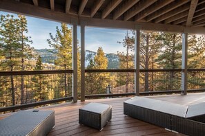 Eine überdachte Terrasse im Freien mit Korbmöbeln und Blick auf eine bewaldete Landschaft.