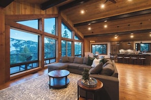 A spacious living area with a large sectional sofa, a round coffee table, and a view of the outdoors through large windows.