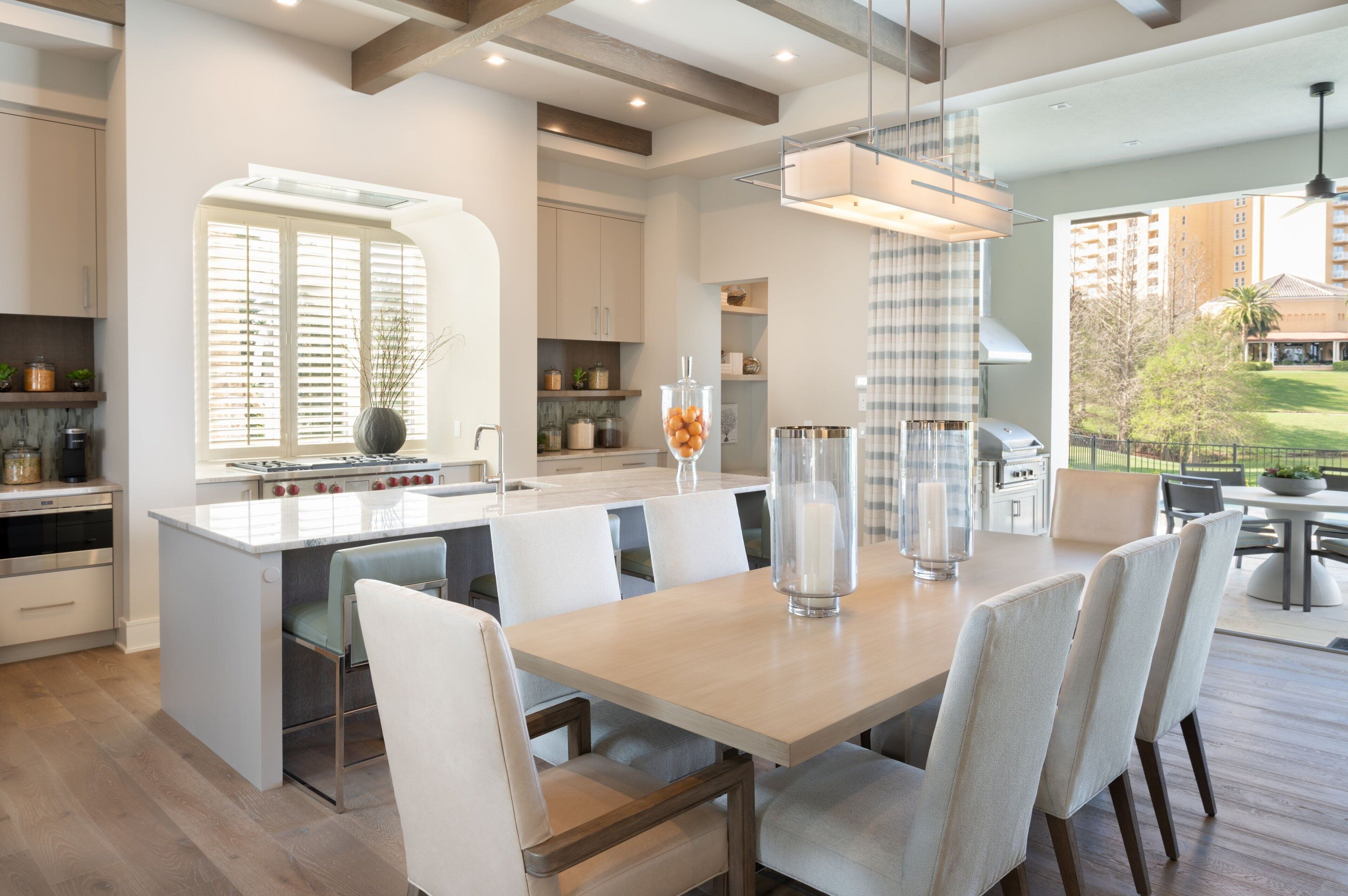 A modern kitchen with a central island, white cabinetry, and a dining area with a large table and chairs.